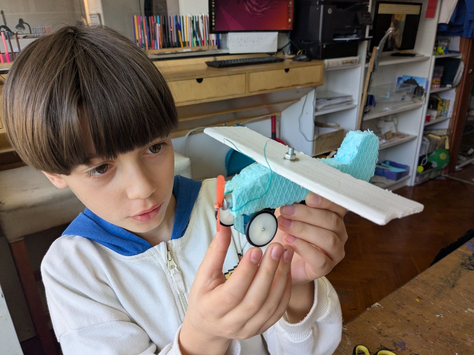 A child closely examining a model plane in the TwoFish environment.